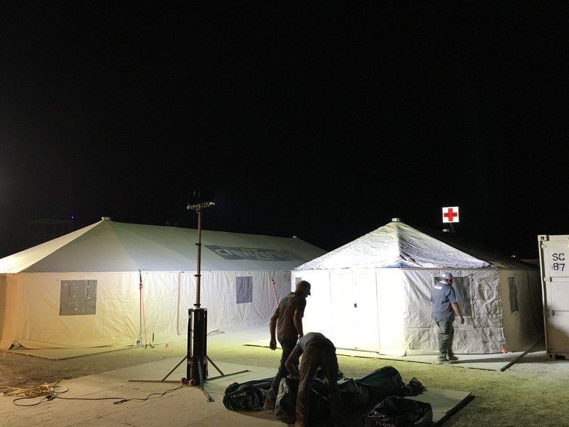 Zwei Zelte mit rotem Kreuz bei Nacht, davor ein BASELIGHT Lichtmast und zwei Helfer