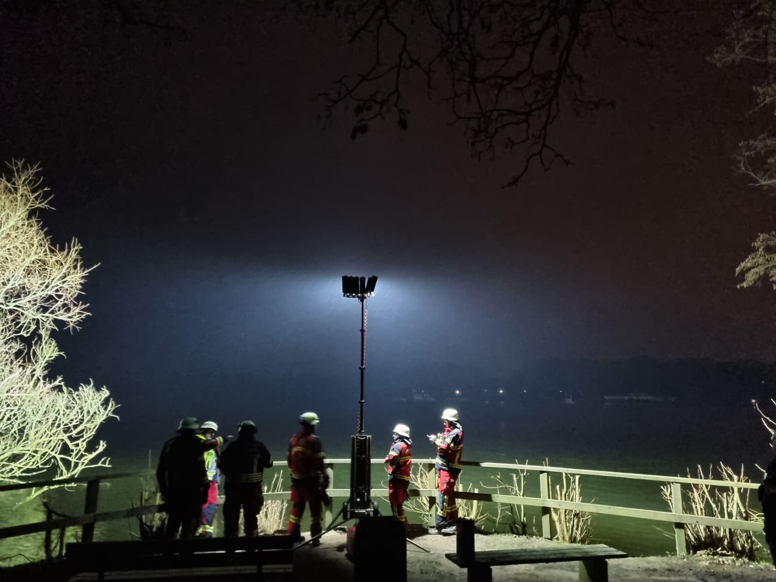 Einsatzkräfte der Feuerwehr bei Nacht an einem Seeufer, ein ausgefahrener BASELIGHT Lichtmast leuchtet den Platz aus